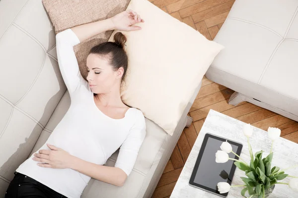 Jeune femme avec une tablette PC sur le canapé — Photo