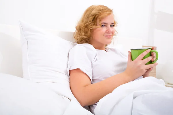 Mujer joven bebiendo café en la cama — Foto de Stock