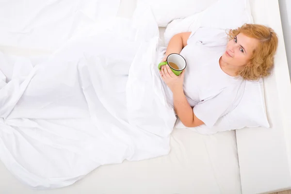 Jeune femme buvant du café au lit — Photo