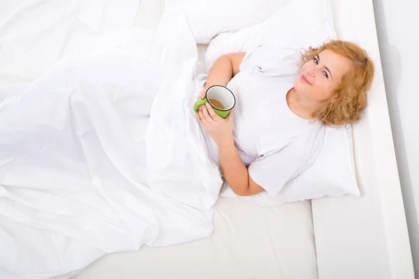 Mujer joven bebiendo café en la cama — Foto de Stock