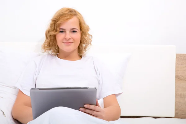 Mujer joven con un Tablet Pc en la cama —  Fotos de Stock