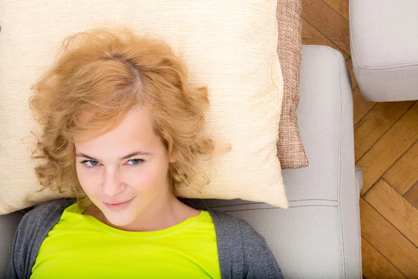 Eine junge lächelnde Frau, die sich auf dem Sofa entspannt. — Stockfoto