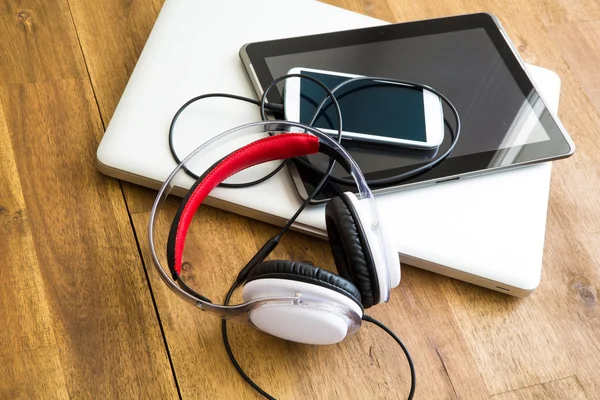 Dispositivos digitais e fones de ouvido em um desktop de madeira — Fotografia de Stock