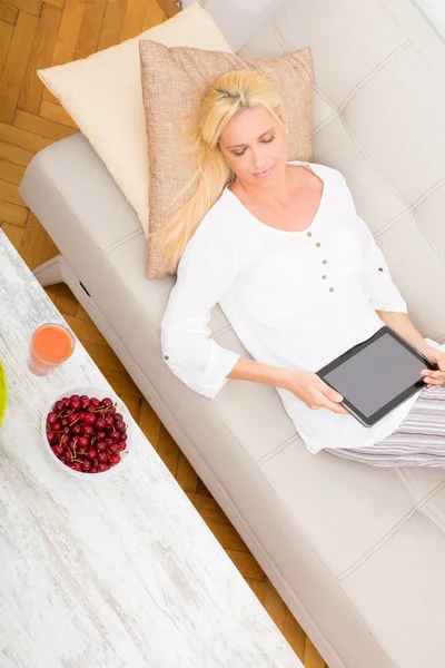 平板电脑和樱桃在沙发上的女人 — 图库照片
