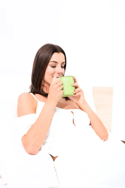 Mooie jonge vrouw, met haar eerste koffie in bed — Stockfoto