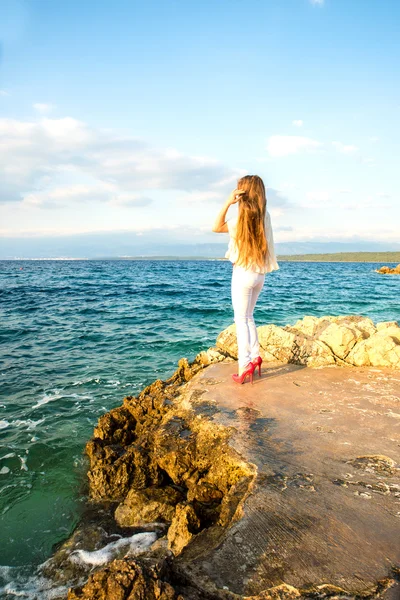 Beautiful young woman looking at the ocean — Stock Photo, Image