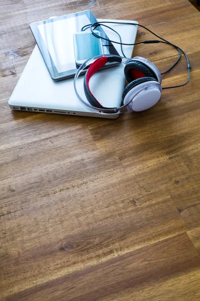 Dispositivos digitales y auriculares en un escritorio de madera —  Fotos de Stock