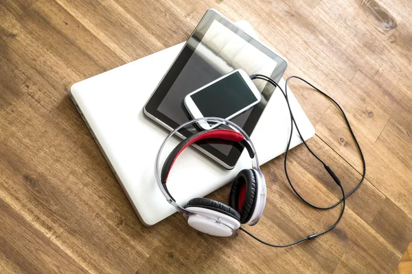 Dispositivos digitales y auriculares en un escritorio de madera —  Fotos de Stock