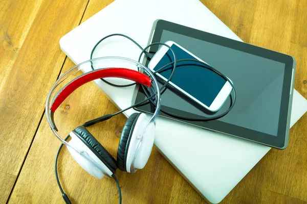 Dispositivos digitales y auriculares en un escritorio de madera —  Fotos de Stock