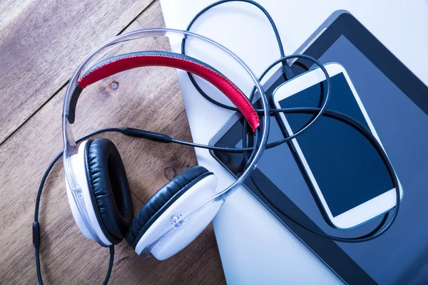 Dispositivos digitales y auriculares en un escritorio de madera —  Fotos de Stock