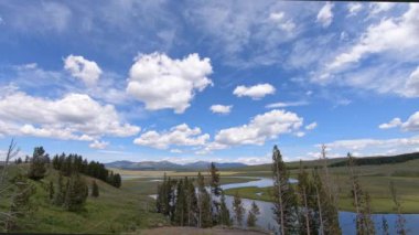 Yellowstone Ulusal Parkı 'ndaki Büyük Döngü Yolu boyunca Hayden Vadisi' nde kümülüs bulutları. Kamera soldan sağa dönerken bulutlar sağa sola hareket ediyor.