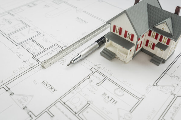 Model Home, Engineer Pencil and Ruler Resting On House Plans