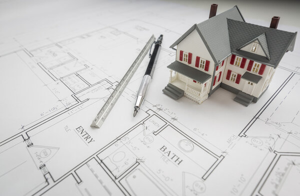 Model Home, Engineer Pencil and Ruler Resting On House Plans