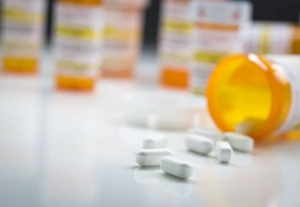 Botellas de la medicina detrás de las píldoras que se derraman de la botella caída —  Fotos de Stock