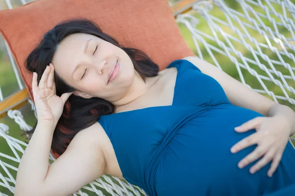 Молодая беременная китаянка отдыхает в гамаке — стоковое фото