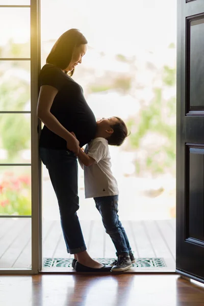 Kleiner Sohn umarmt schwangere Mutter in Tür — Stockfoto