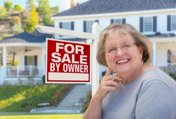 Mujer adulta mayor frente al cartel de bienes raíces, Casa —  Fotos de Stock