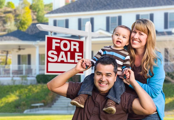 Joven familia en frente de en venta signo y casa — Foto de Stock