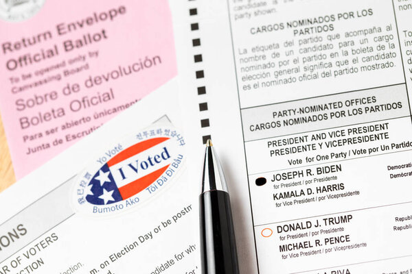 Риверсайд, Калифорния, США - 10 / 2020: Перо, лежащее на Байдене голосовал Официальное голосование, конверт, инструкции и я голосовал наклейка на стол в 2020 Президентские выборы.