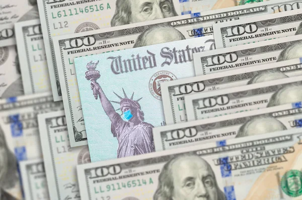 米国Irs刺激チェックの自由の女神を身に着けている医療面マスク百ドル札に安静時 — ストック写真