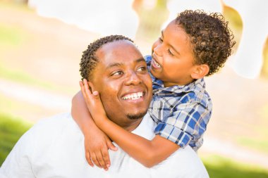 Mutlu Afrikalı Amerikalı Baba ve Karışık Irk Oğlu parkta oynuyor.