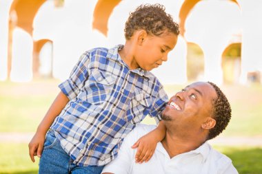 Mutlu Afrikalı Amerikalı Baba ve Karışık Irk Oğlu parkta oynuyor.