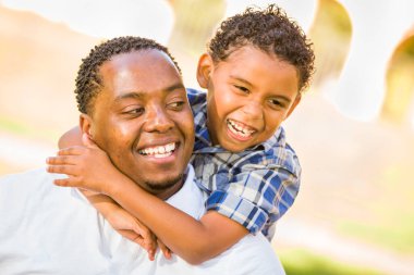 Mutlu Afrikalı Amerikalı Baba ve Karışık Irk Oğlu parkta oynuyor.