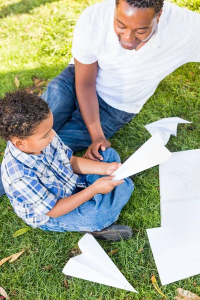 公園で紙飛行機と遊ぶ幸せなアフリカ系アメリカ人の父と混合レースの息子 — ストック写真