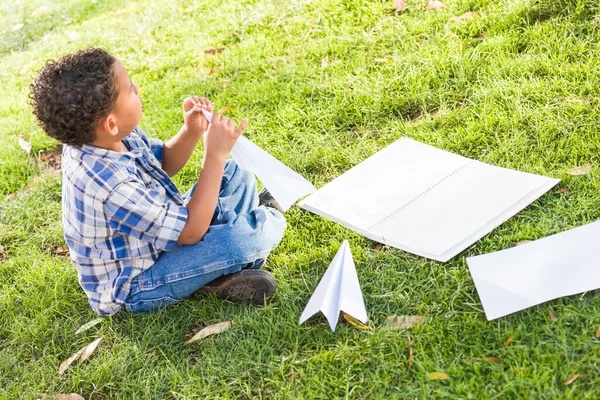 アフリカ系アメリカ人とメキシコ人の少年紙飛行機を草の上に折る方法を学ぶ — ストック写真