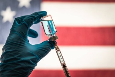 Amerikan Bayrağına Karşı Koronavirüs Aşısı veya Tıbbı Siluetiyle Dolu Ön Hat İşçisi Şırınga ve Şırınga Tutuyordu.