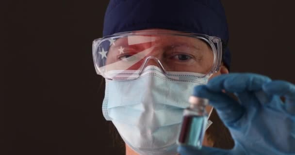 แพทย อพยาบาลสวมหน ากากใบหน าทางการแพทย และแว นตาท ธงอเมร นสะท อนแสงถ อขวดว — วีดีโอสต็อก