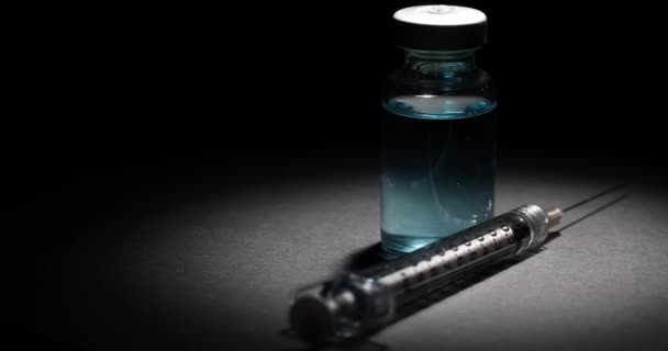 Vial Jeringa Vacuna Médica Spot Lit Girando Sobre Superficie Negra — Vídeo de stock
