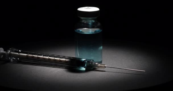 Spot Lit Medical Vaccine Vial Syringe Rotating Black Surface Dark — Stock Video