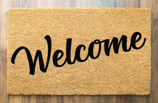 Tan Welcome Mat On Wood Floor Background..