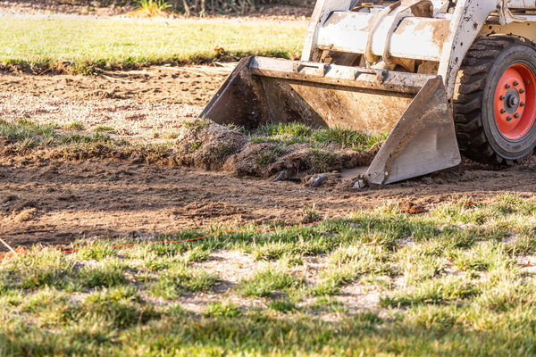 Small Bulldozer Removing Grass From Yard Preparing For Pool Installation.