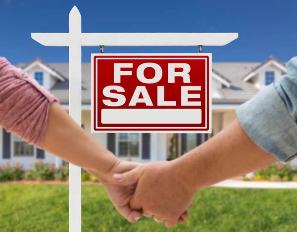 美しい新しい家の前で手を握り 販売のためのカップル不動産標識 — ストック写真