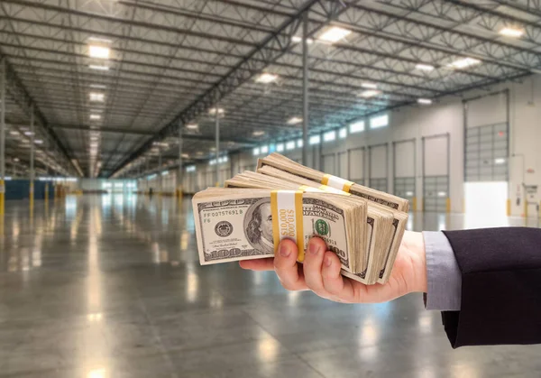 Mannelijke Hand Holding Duizenden Dollars Binnen Leeg Industrieel Pakhuis — Stockfoto