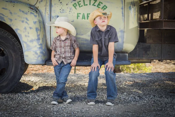 两个小男孩头戴牛仔帽倚着古色古香的卡车在一个乡村国家设置 — 图库照片