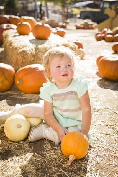 Schattige babymeisje houden een pompoen op de pompoen patch — Stockfoto