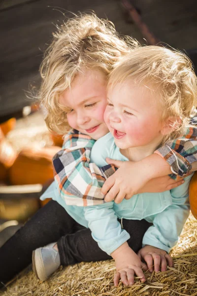 Liten pojke leker med hans lillasyster på pumpkin patch — Stockfoto