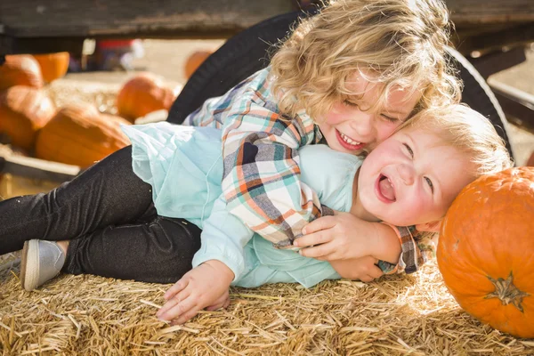 Kisfiú játszik a baba húga pumpkin patch — Stock Fotó