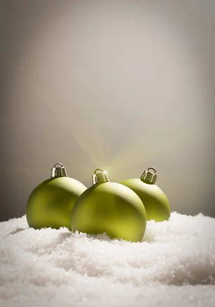 Πράσινο χριστουγεννιάτικα στολίδια στο χιόνι πάνω από ένα γκρίζο φόντο — Φωτογραφία Αρχείου