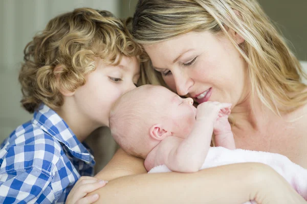 Giovane madre tiene neonato bambina come fratello guarda — Foto Stock