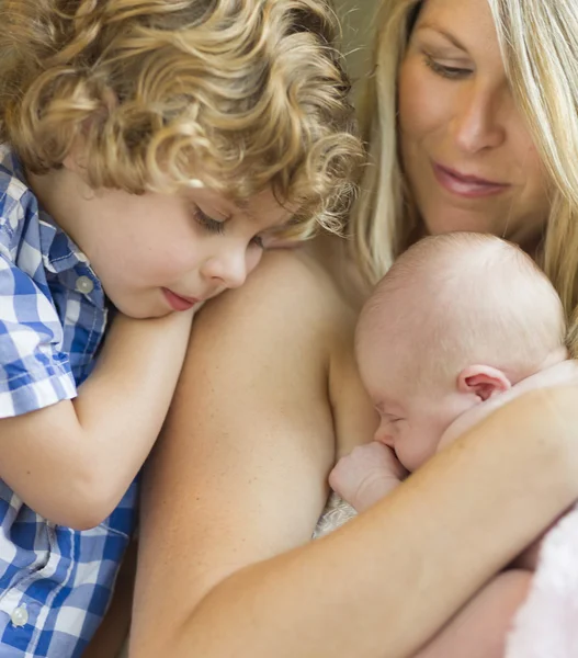 Jeune mère tient le nouveau-né fille comme frère regarde — Photo