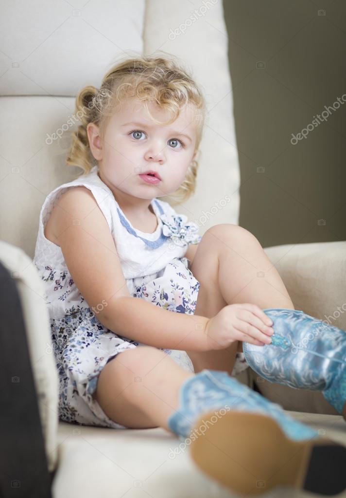Blonde Haired Blue Eyed Little Girl Putting On Cowboy Boots