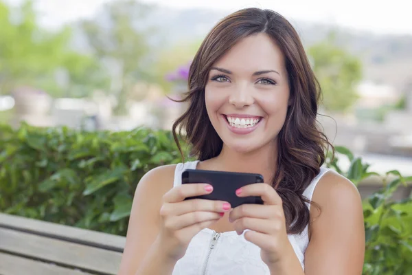 Χαμογελαστός νεαρός ενήλικο θηλυκό γραπτών μηνυμάτων στο κινητό τηλέφωνο σε εξωτερικούς χώρους — Φωτογραφία Αρχείου