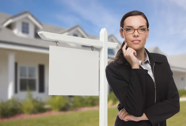 Mujer en frente de la casa y el signo de bienes raíces en blanco —  Fotos de Stock