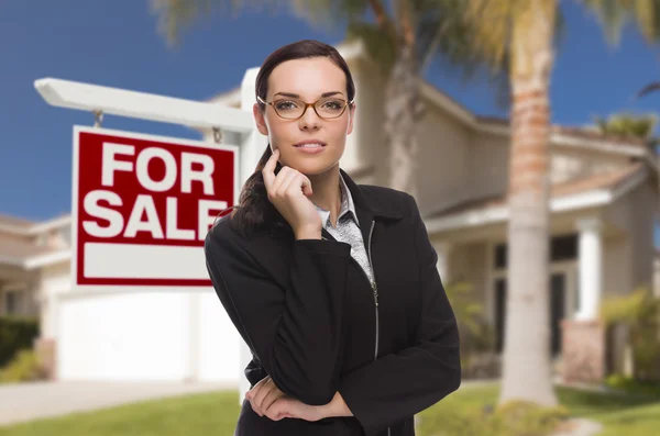 Jonge vrouw voor huis en verkoop teken — Stockfoto