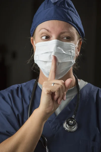 Geheimzinnige vrouwelijke arts met vinger voor mond — Stockfoto