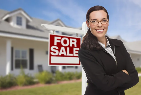 Jonge vrouw voor huis en verkoop teken — Stockfoto